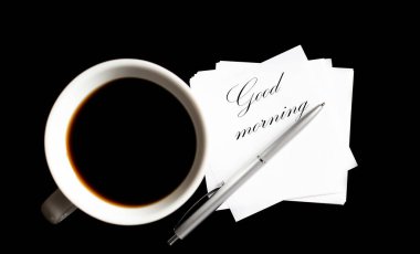 Ofis masasında kahve fincanı ve malzeme var. Metin için yukarıdan görüntüle Günaydın