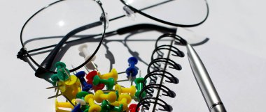 Beyaz arka plan iş konsepti üzerine gözlüklü, karanfilli ve kalemli boş defter