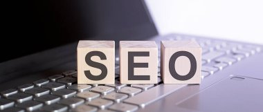 Dizüstü bilgisayarında SEO konsept metni olan tahta bloklar