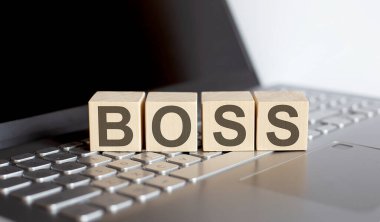 Dizüstü bilgisayarında BOSS konsept metni olan tahta bloklar