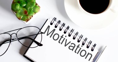 Not defterinde bardaklar ve bir fincan kahveyle motivasyon metni