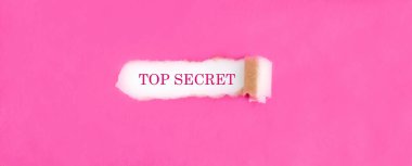 Yırtık pembe kağıdın arkasında gizli metin.