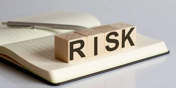 ノートブック背景の木製ブロック上のリスクサイン — ストック写真