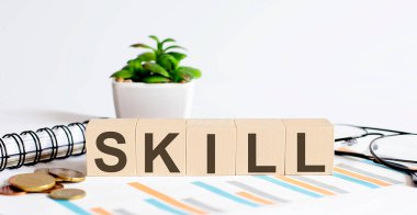 Grafik, sikke, defter ve gözlüklerle ağaç blokları kavramı üzerine tek kelime.