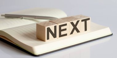 Defter arkaplanındaki tahta bloktaki NEXT işareti