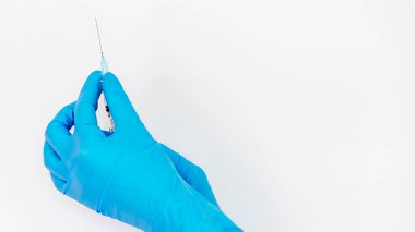 Mavi eldivenli bir el beyaz arka planda bir şırınga tutuyor.