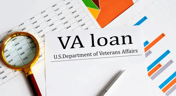 Paper with VA loan on table with charts, pen and magnifier