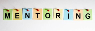 MENTORING ifadesi beyaz arkaplanda çok renkli çıkartmalara yazılmıştır. İş konsepti, strateji, plan, planlama.