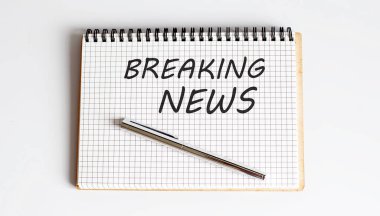 Son dakika haberlerini gösteren bir not yazıyorum. Beyaz arkaplanda beyaz not defteri ve kalem