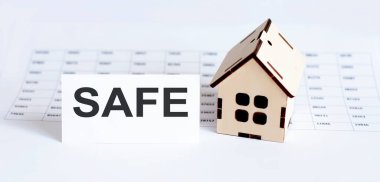 Dosya arkaplanında boş ve metin SAFE olan ev ahşap modelinin yakınlaştırılması.