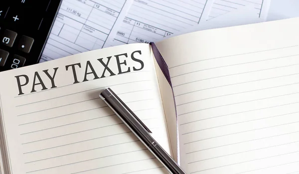 税金の支払いに関するツールと注意事項を記載したノート — ストック写真