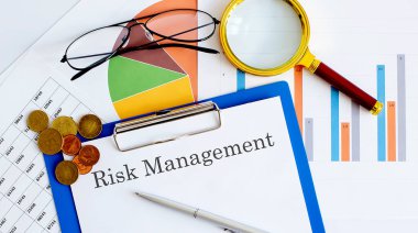 RISK MANAGEMENT İş Raporları, boş kağıt, veri tabloları ve grafikler, büyüteç, madeni paralar - ofis masasının tam üstünde