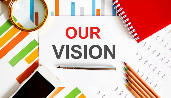 Text OUR VISION on the notepad with office tools, pen on financial report