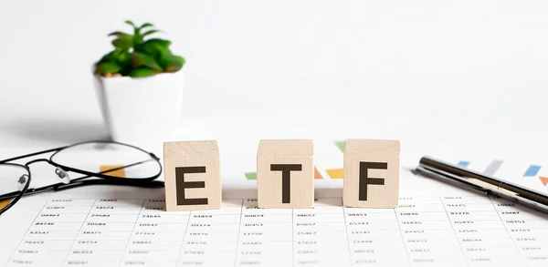 ETF kelime kavramı tahta bloklara yazılır, küpler çiçek, kalem ve bardaklar arkaplanda