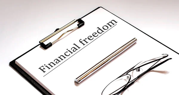 ペンとメガネ付きホワイトシート上の金融自由の概念 — ストック写真