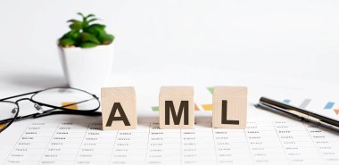 Tahta bloklara yazılmış AML sözcük kavramı, çiçekli bir masanın üzerindeki küpler, çizelgede kalem ve bardaklar.