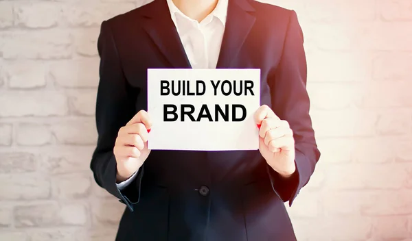 woman showing white card with BUILD YOUR BRAND word . Business concept