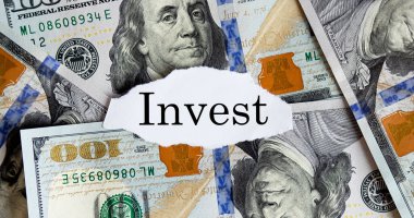 Yırtık kağıt üzerinde INVEST finans metni ile ABD doları. İş konsepti