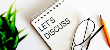 DISCUSS - beyaz bir defter ve gözlük, kalem, yeşil çiçekler üzerinde iş konsepti metni