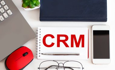 Dolma kalemli CRM metni, dekoratif bitki, klavye ve tahta arka planda not defteri. İş konsepti