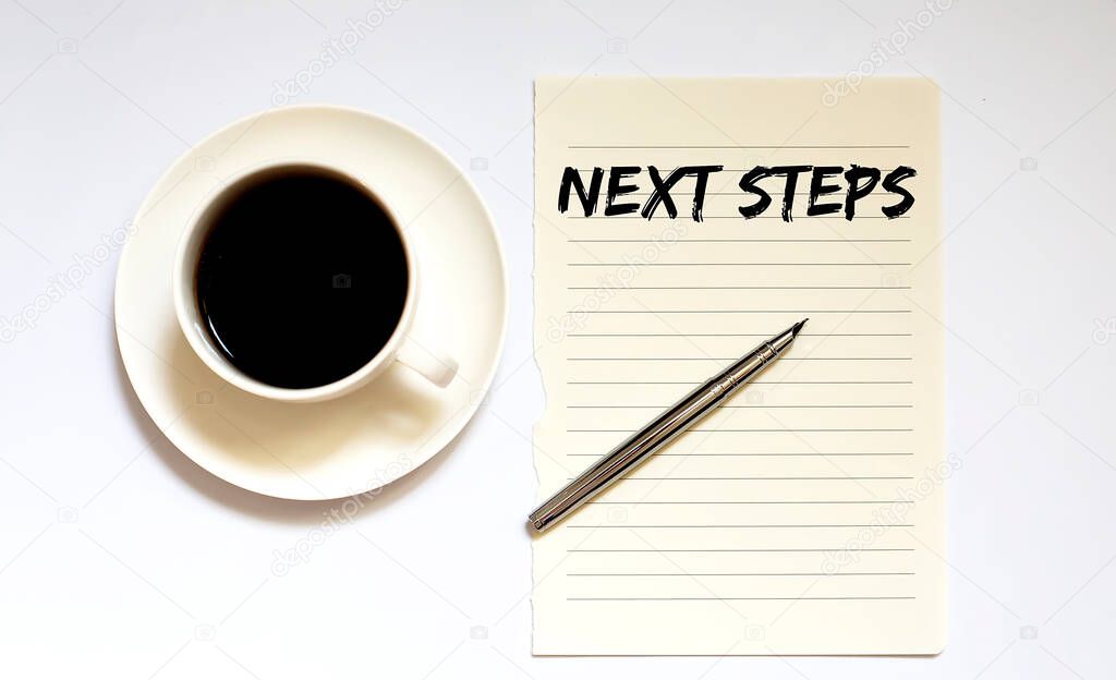 NEXT STEPS - white paper with pen and coffee on wooden background. Business