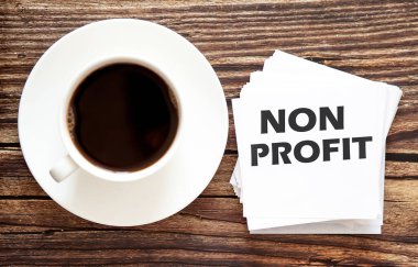 Kelime yazma metni NON PROFIT. Acil Hareketler için iş konsepti. Üzerinde beyaz etiketler ve kahve kapağı olan bir metin.