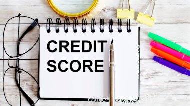 Ofis araçları ile beyaz arkaplan üzerine not defteri ile yazılmış CREDIT skorları