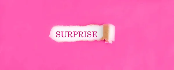 破れたピンクの紙の後ろに現れるテキストTsurprise — ストック写真