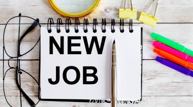 Ofis araçları ile beyaz arkaplan üzerine bir deftere yazılmış NEW JoB