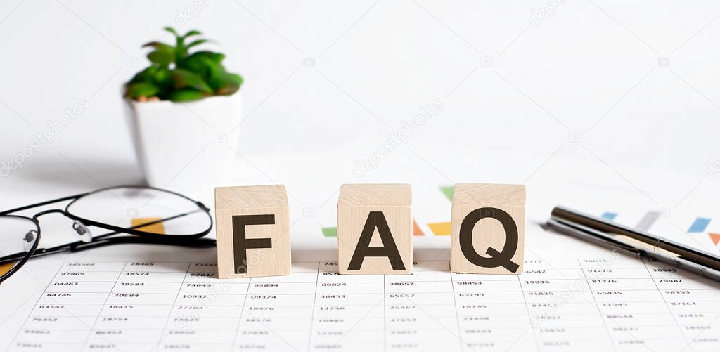 text of FAQS on the wooden cubes on chart with pen and glasses