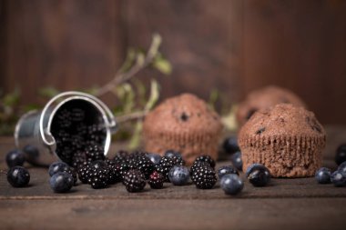 Çikolata muffin koyu ahşap arka plan blackberry ile dekore edilmiş
