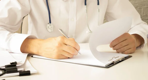 Young therapist filling medical checklist sitting at the desk. Health care and insurance concept.