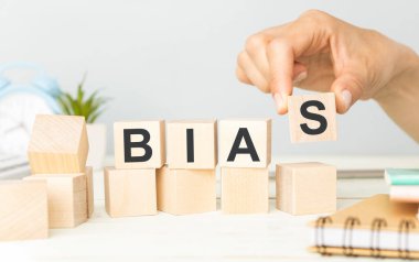 BIAS kelimesi, beyaz bir arkaplan üzerinde ahşap harflerle yazılıyor..