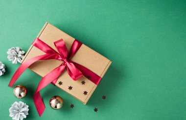 Kahverengi hediye kutusuna ve yeşil arka planda kırmızı kurdeleye bakın. Yılbaşı ve Noel hediyeleri konsepti.