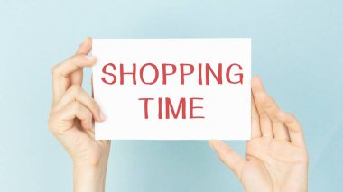 Mavi arkaplanda el altından alışveriş yapmak için metin zamanı olan boş bir kağıt parçası