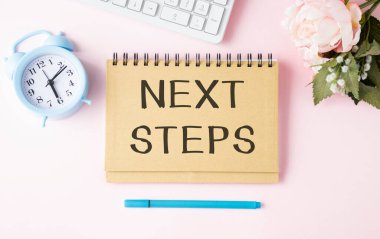 Not defterindeki bir sonraki STEPS mesajını tahta masada bardak, kalem ve kahve fincanı ile kavra.