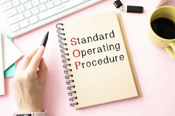 Standart İşletim Prosedürü metni kağıt üzerine açık günlükte gözlük, renkli raptiye, tahta masa üzerinde kalem ve hesap makinesi - iş ve finans kavramı