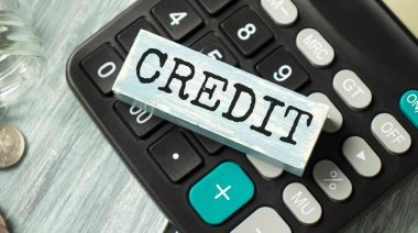 Tahta bloklu CREDIT ile nakit para, hesap makinesi, anahtar ve mini ev. Emlak Konsepti - Ahşap blokta yazılı olan ev