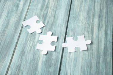 Tahta bir arka planda beyaz yapboz parçaları var.