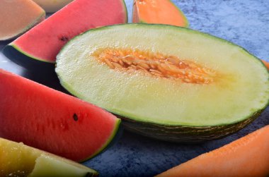 Lezzetli organik kavunlar ve karpuz mavi taş arka planda ikiye bölünmüş.