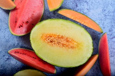 Lezzetli organik kavunlar ve karpuz mavi taş arka planda ikiye bölünmüş.
