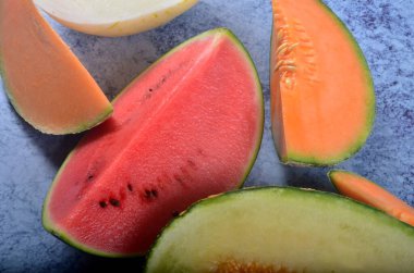 Lezzetli organik kavunlar ve karpuz mavi taş arka planda ikiye bölünmüş.