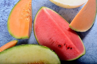 Lezzetli organik kavunlar ve karpuz mavi taş arka planda ikiye bölünmüş.