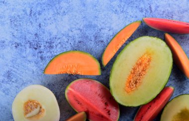 Taze kesilmiş kavunlar ve mavi taştan bir arka planda karpuz. Boşluk ve metin alanını kopyala