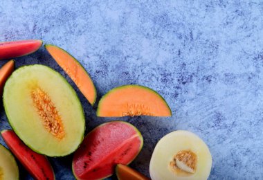 Taze kesilmiş kavunlar ve mavi taştan bir arka planda karpuz. Boşluk ve metin alanını kopyala