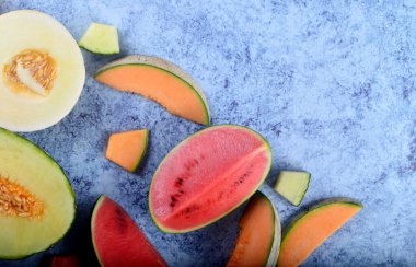 Taze kesilmiş kavunlar ve mavi taştan bir arka planda karpuz. Boşluk ve metin alanını kopyala