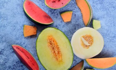 Taze kesilmiş kavunlar ve mavi taştan bir arka planda karpuz. Boşluk ve metin alanını kopyala