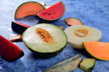 Taze kesilmiş kavunlar ve mavi taştan bir arka planda karpuz. Boşluk ve metin alanını kopyala