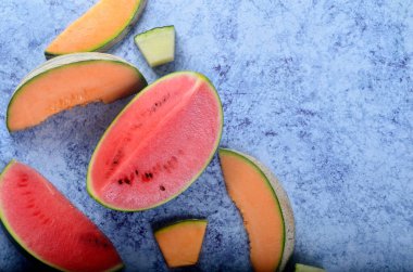 Taze kesilmiş kavunlar ve mavi taştan bir arka planda karpuz. Boşluk ve metin alanını kopyala