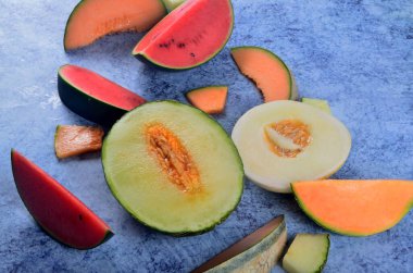 Taze kesilmiş kavunlar ve mavi taştan bir arka planda karpuz. Boşluk ve metin alanını kopyala